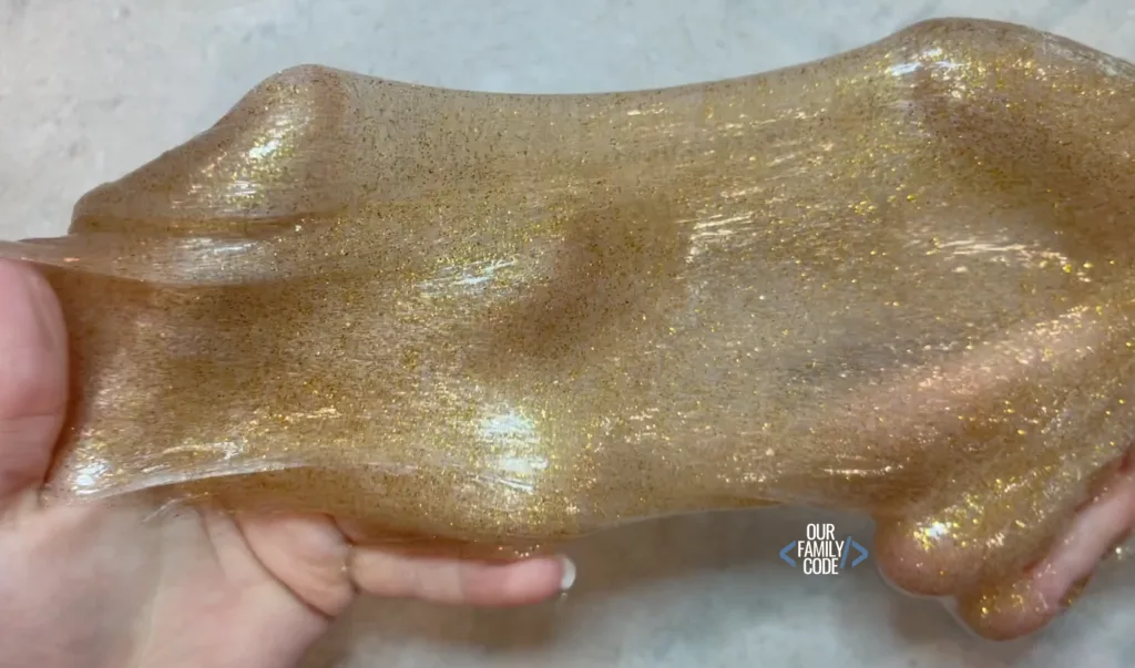 A picture of gold glitter slime being stretched.