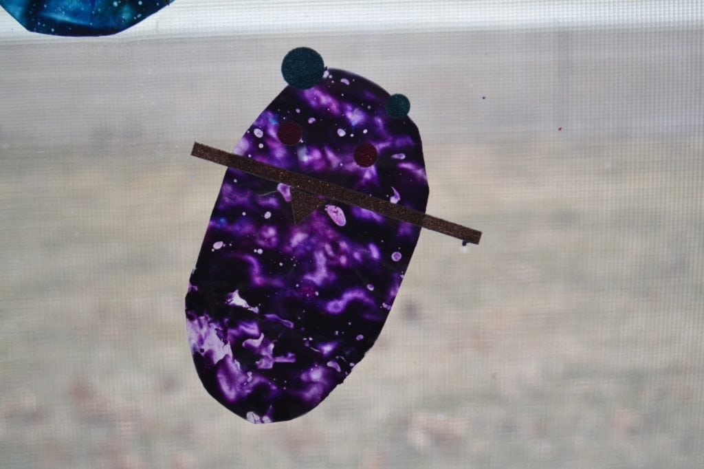 A picture of a mouse sun catcher made from melted crayon shavings.