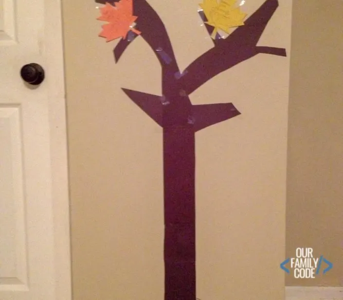 A picture of a freehand cut tree out of brown construction paper with two maple leaves cut in orange and yellow with things that kids are thankful for on them.