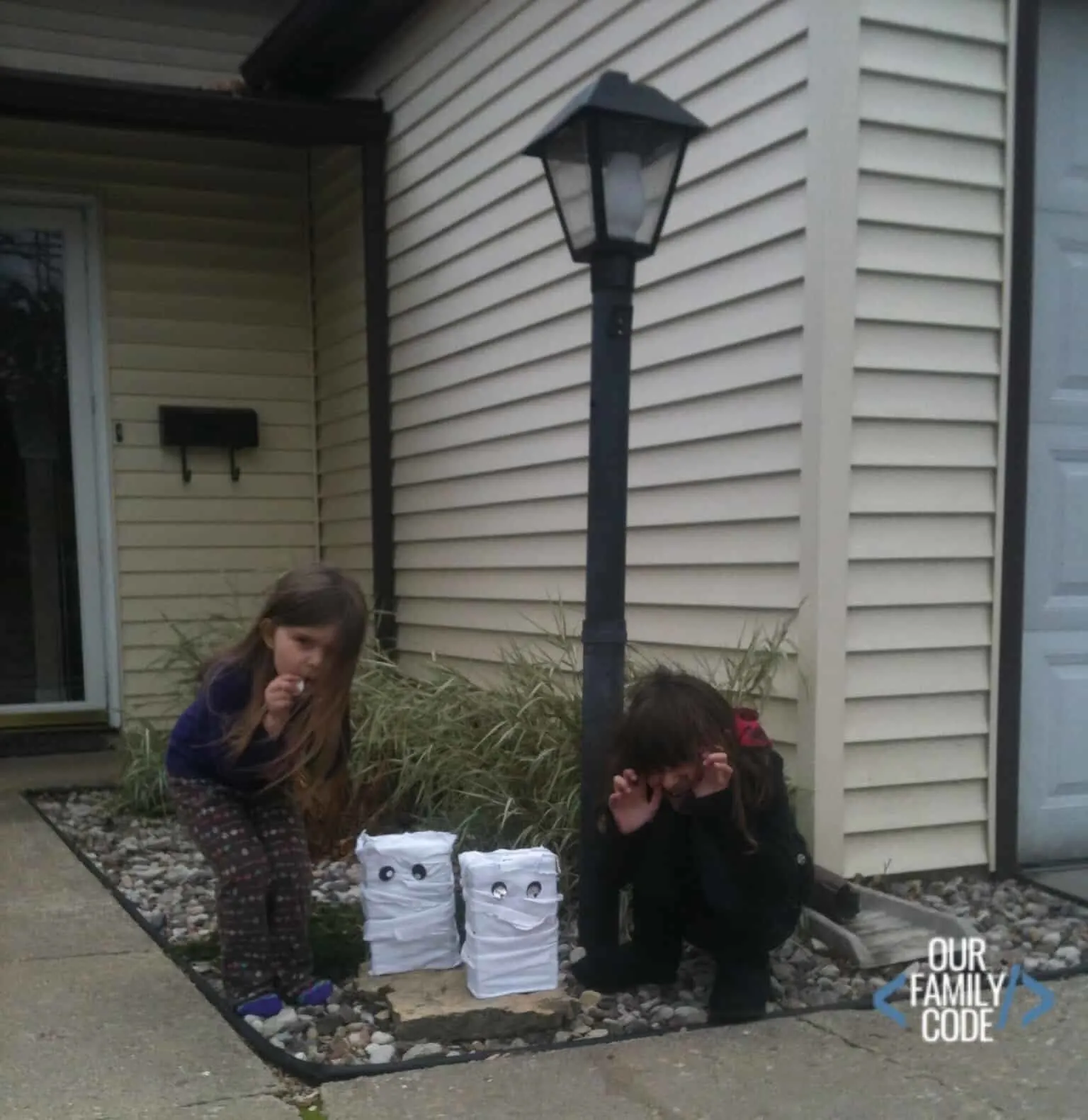 A picture of two girls posing with their recycled art cereal box mummy decoration.