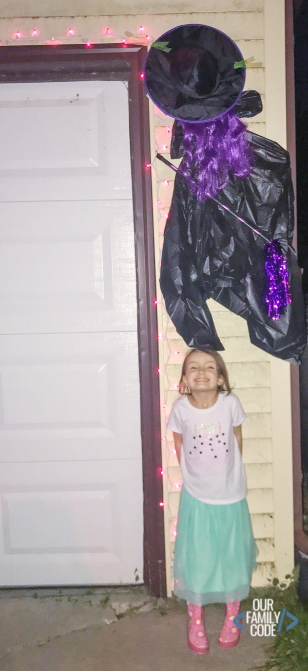 A picture of a DIY Witch crash landing into house with kid smiling.
