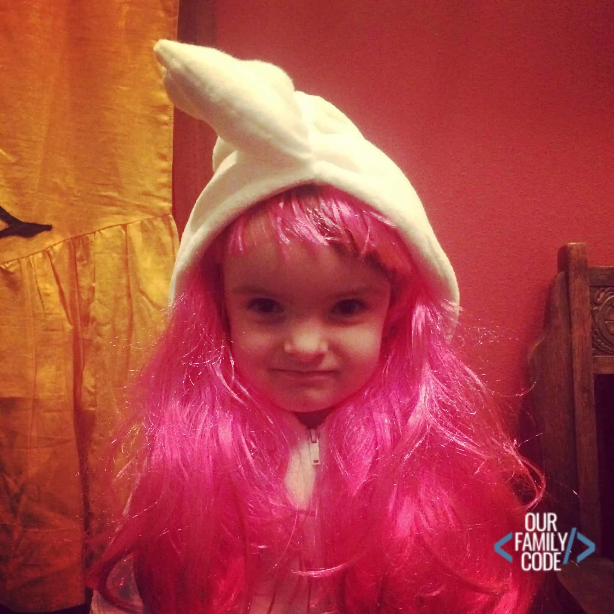 A picture of a kid wearing a bright pink wig.