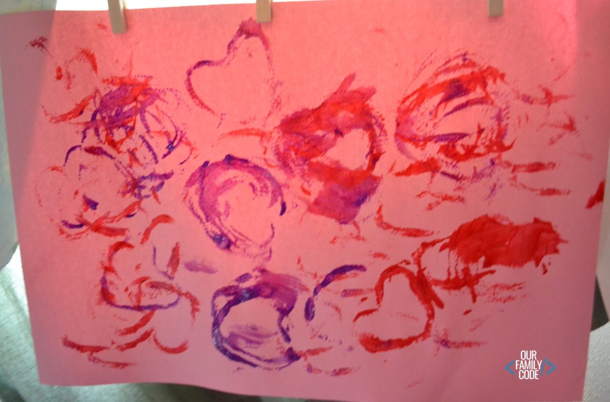 A picture of pipe cleaner painting hearts on construction paper.