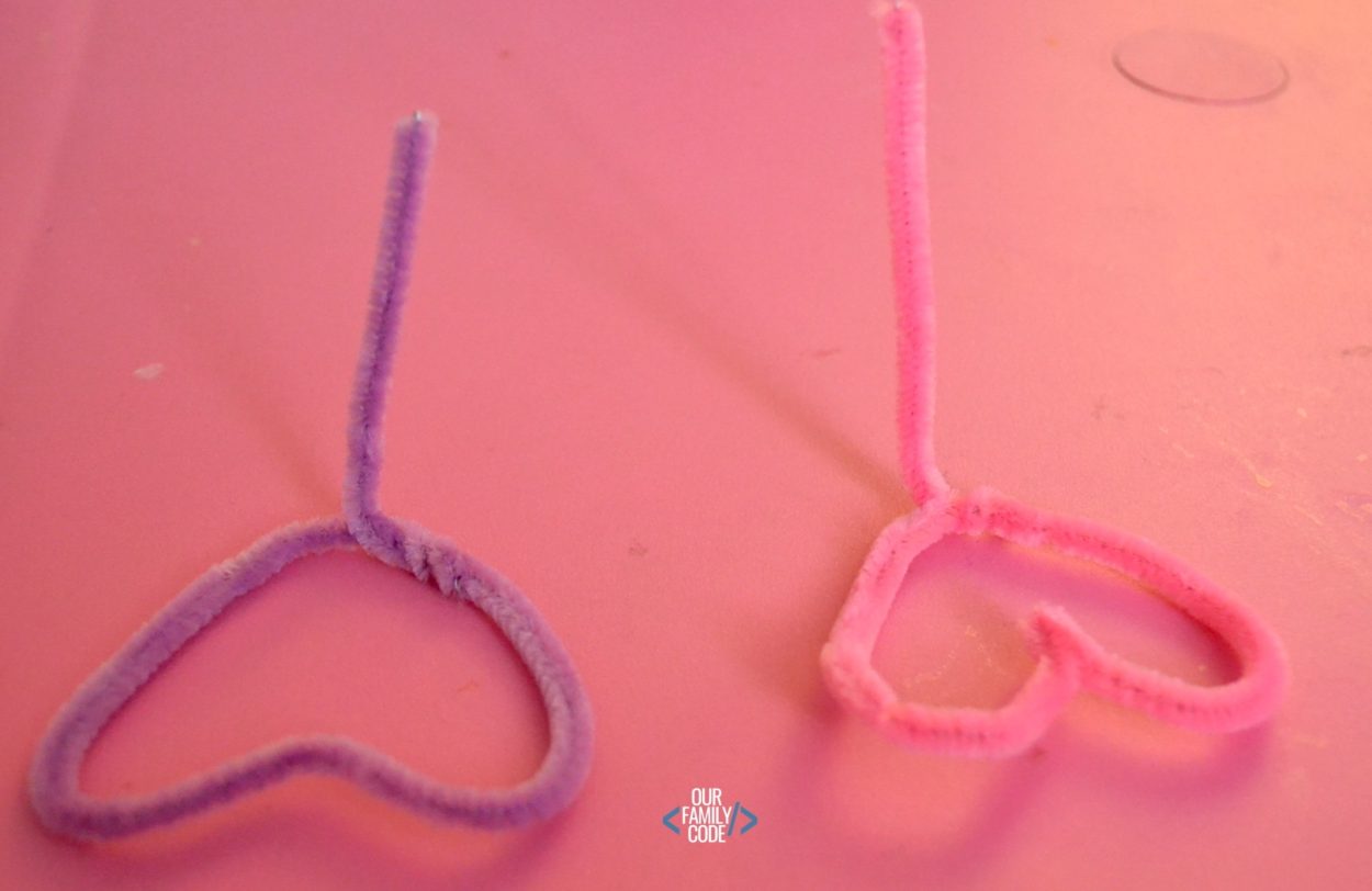 A picture of a heart stamping process art pipe cleaner activity with pipe cleaners made into hearts for painting.