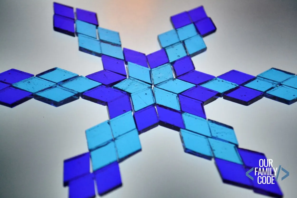 Mosaic pieces are a great way to create an invitation to play for older kids! Find out what you need to make mosaic snowflakes at Our Family Code! #winteractivitiesforkids #kidscrafts #mosaicartwork #tangrams #mathart #STEAM #STEM