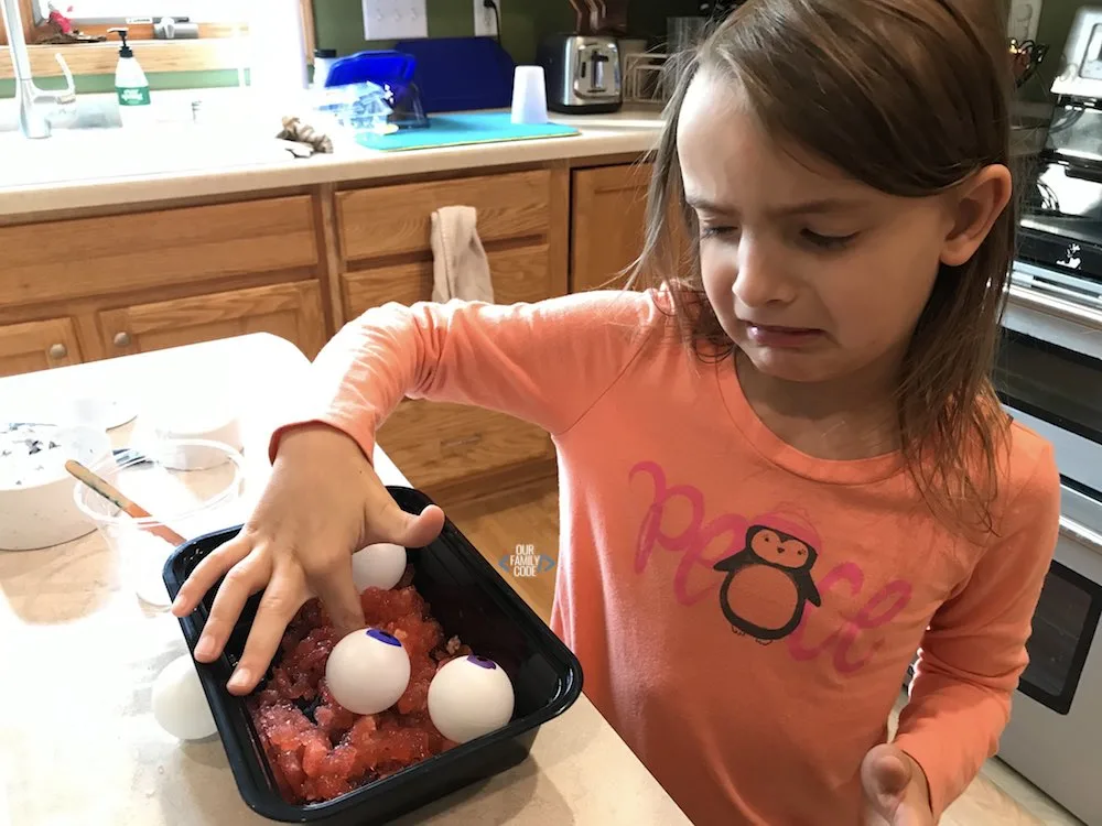 A picture of a kid feeling slime with a sour look on their face.