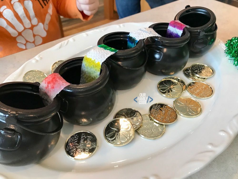 a photo of rainbow walking water stem activity on white plate with gold coins.