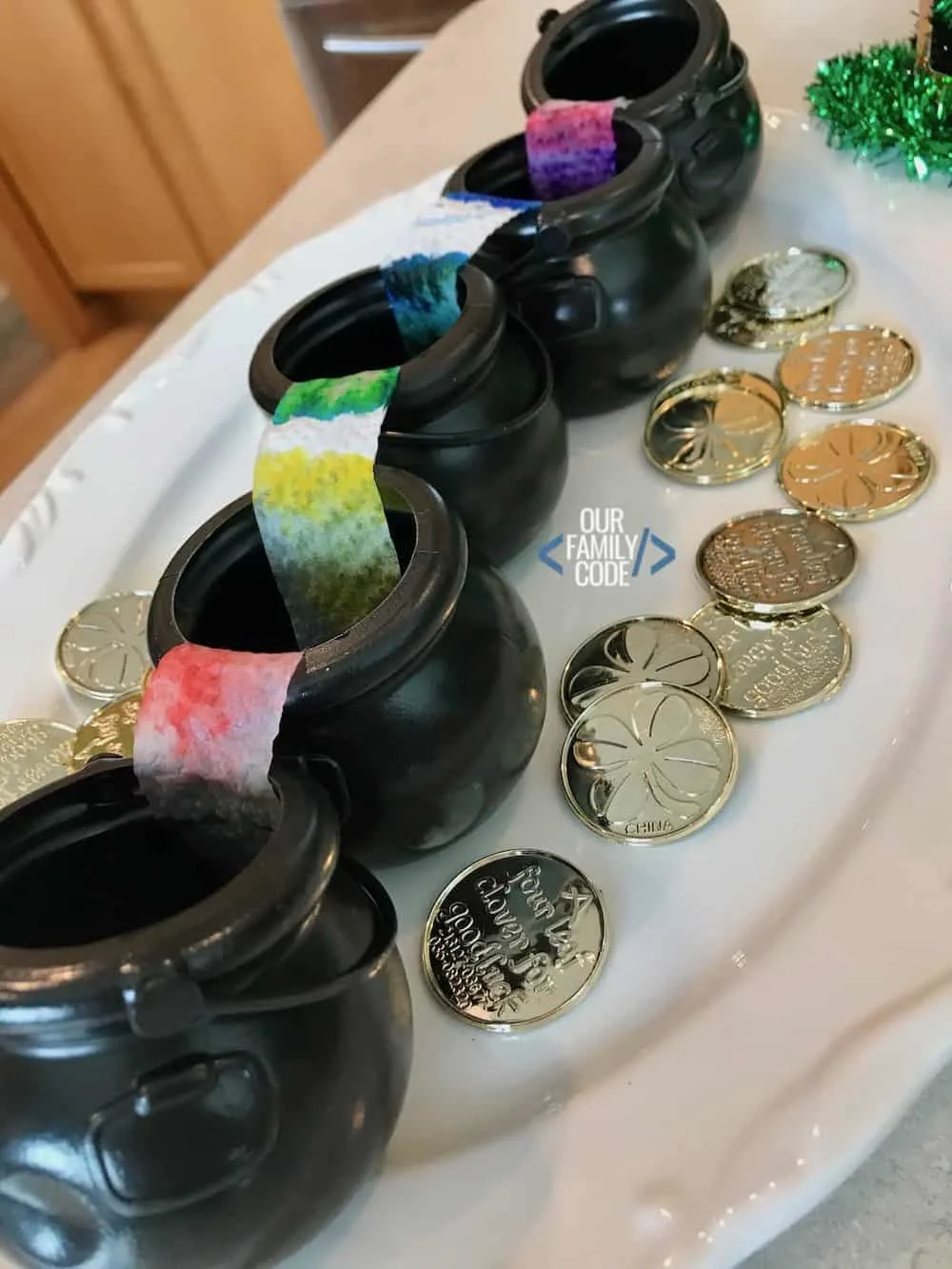 a picture of black cauldrons with rainbow colored paper towels between them with gold coins on a white plate.