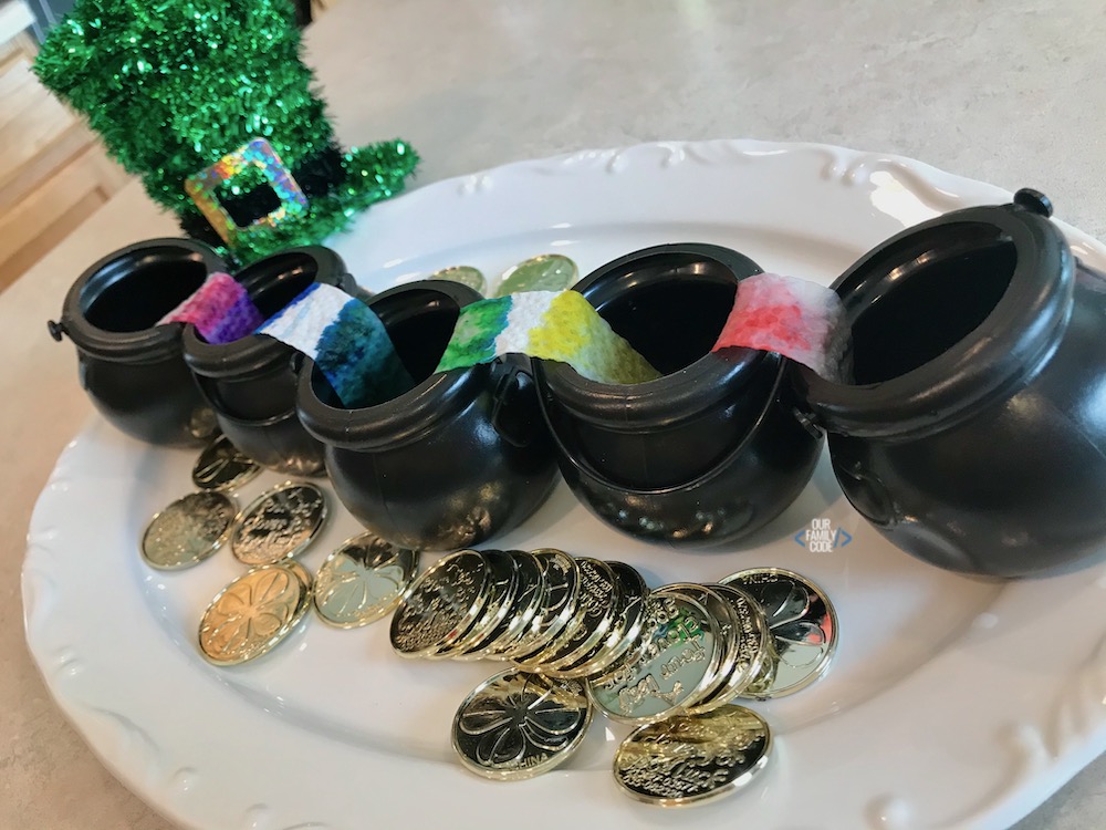 a picture of walking water rainbow activity on a white plate with gold coins. 