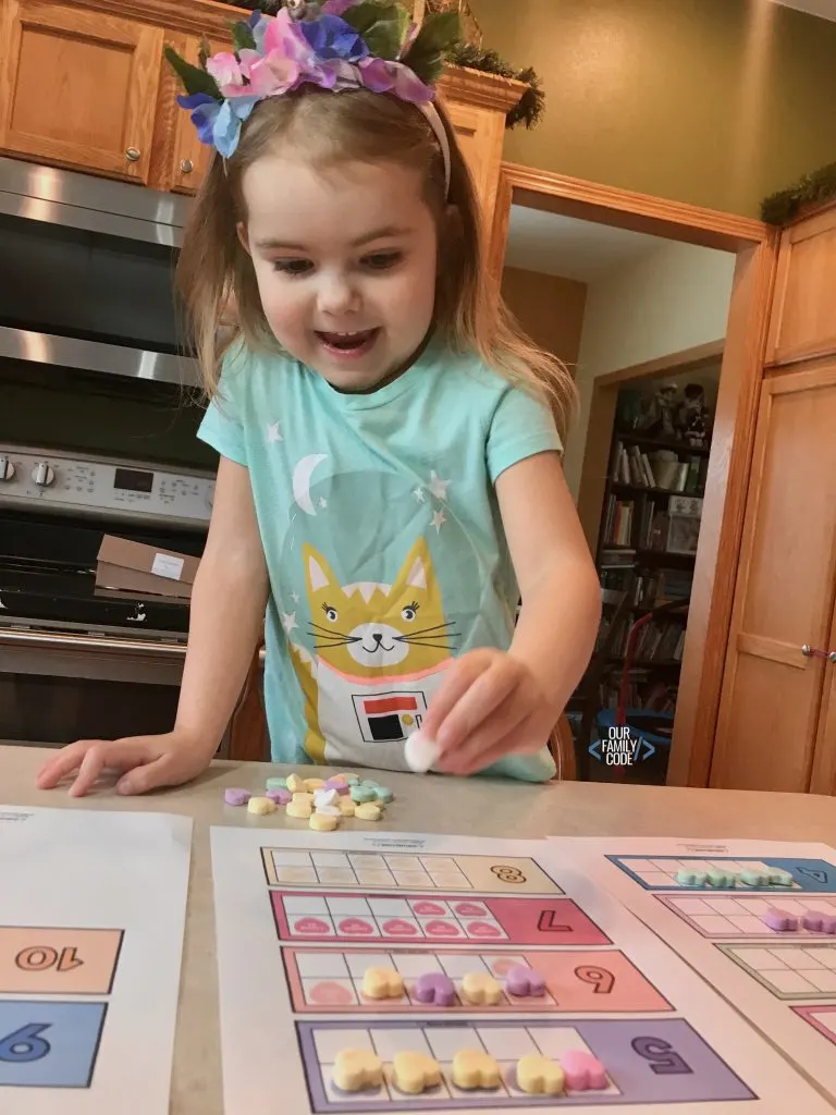 A picture of a preschooler using candy hearts on a ten frame.