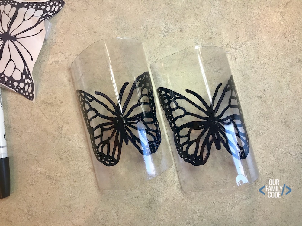A picture of two butterflies drawn on two plastic water bottle halves.