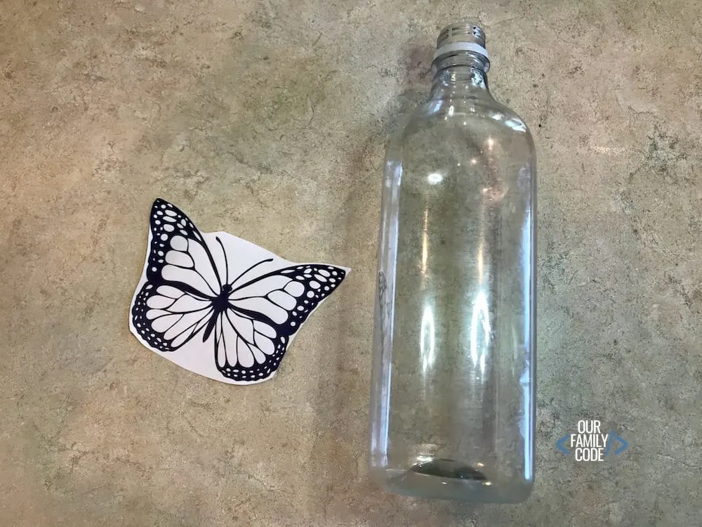 A picture of a black and white butterfly paper with an empty plastic water bottle.