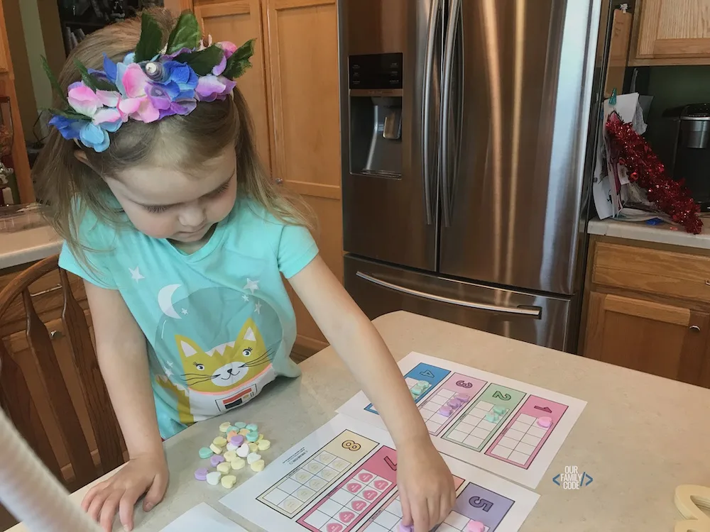 A picture of a preschooler using candy hearts on a ten frame.