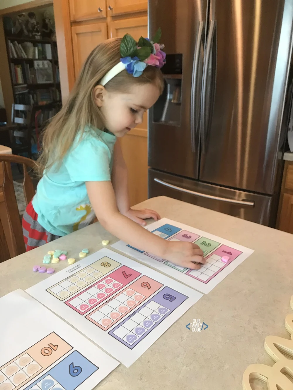 A picture of a preschooler using candy hearts on a ten frame.