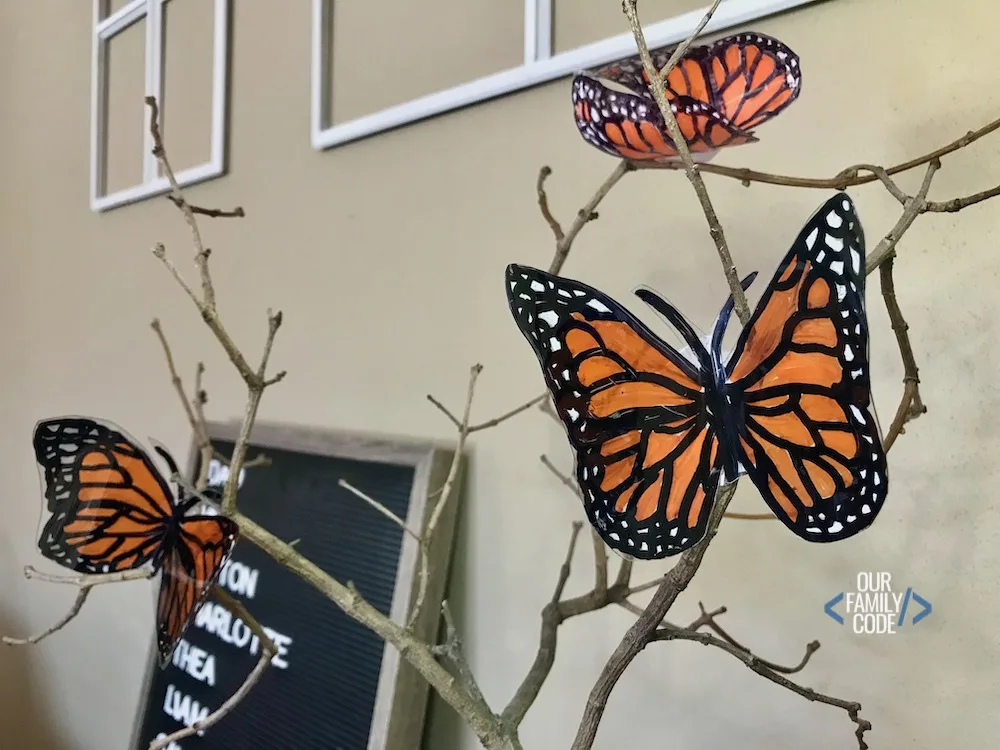 A picture of three plastic bottle butterflies displayed on a branch.