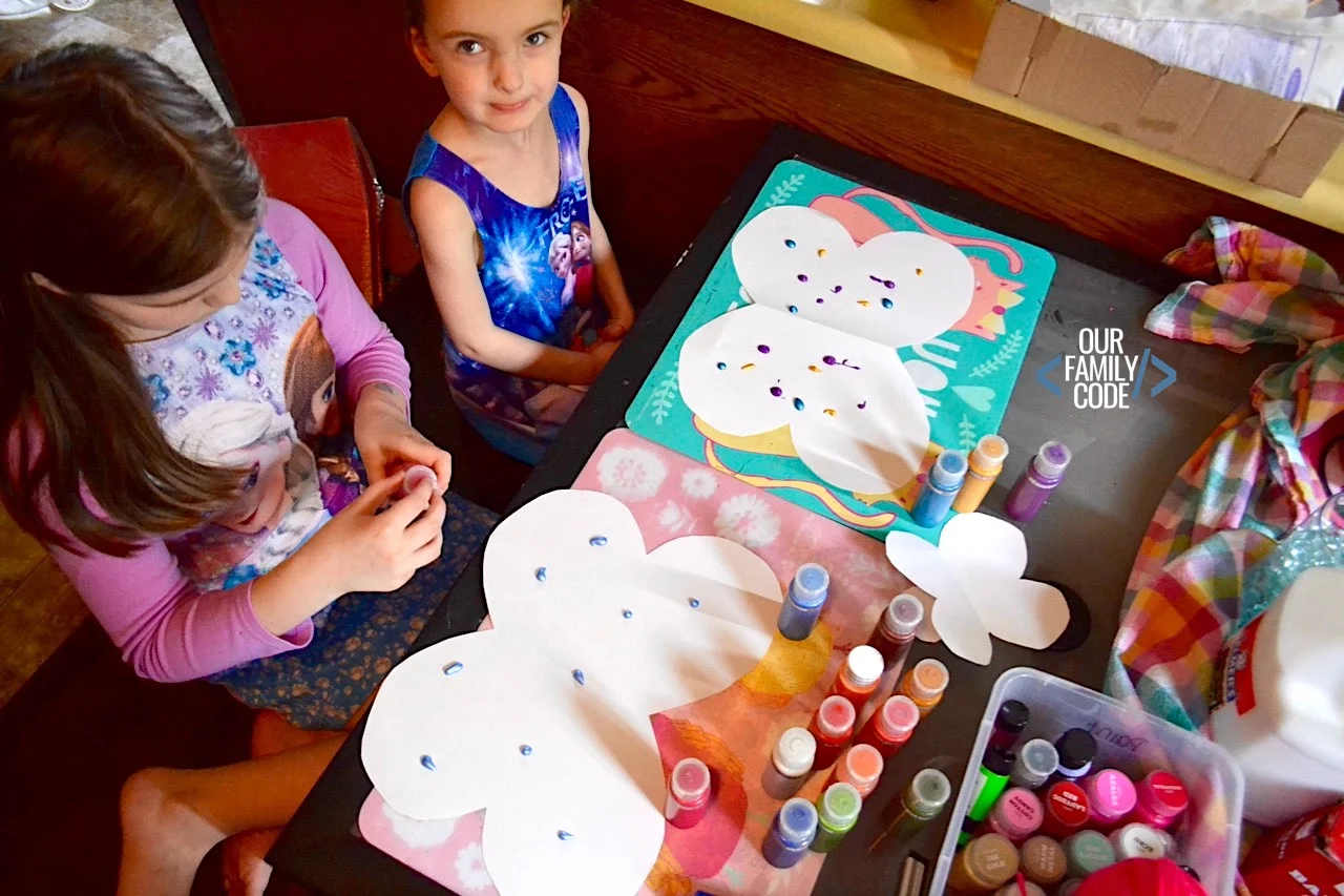 A picture of two kids making squeegee art butterflies.