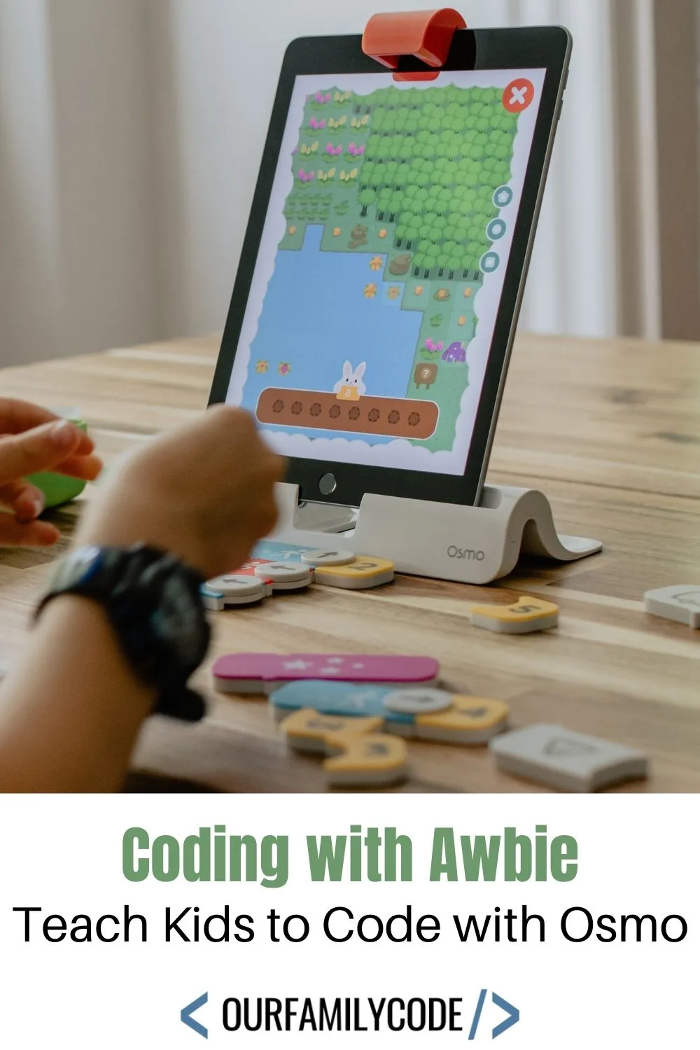 A picture of a kid playing Coding Awbie game from Osmo with text that says "Coding with Awbie Teach Kids to Code with Osmo" over a white rectangle.