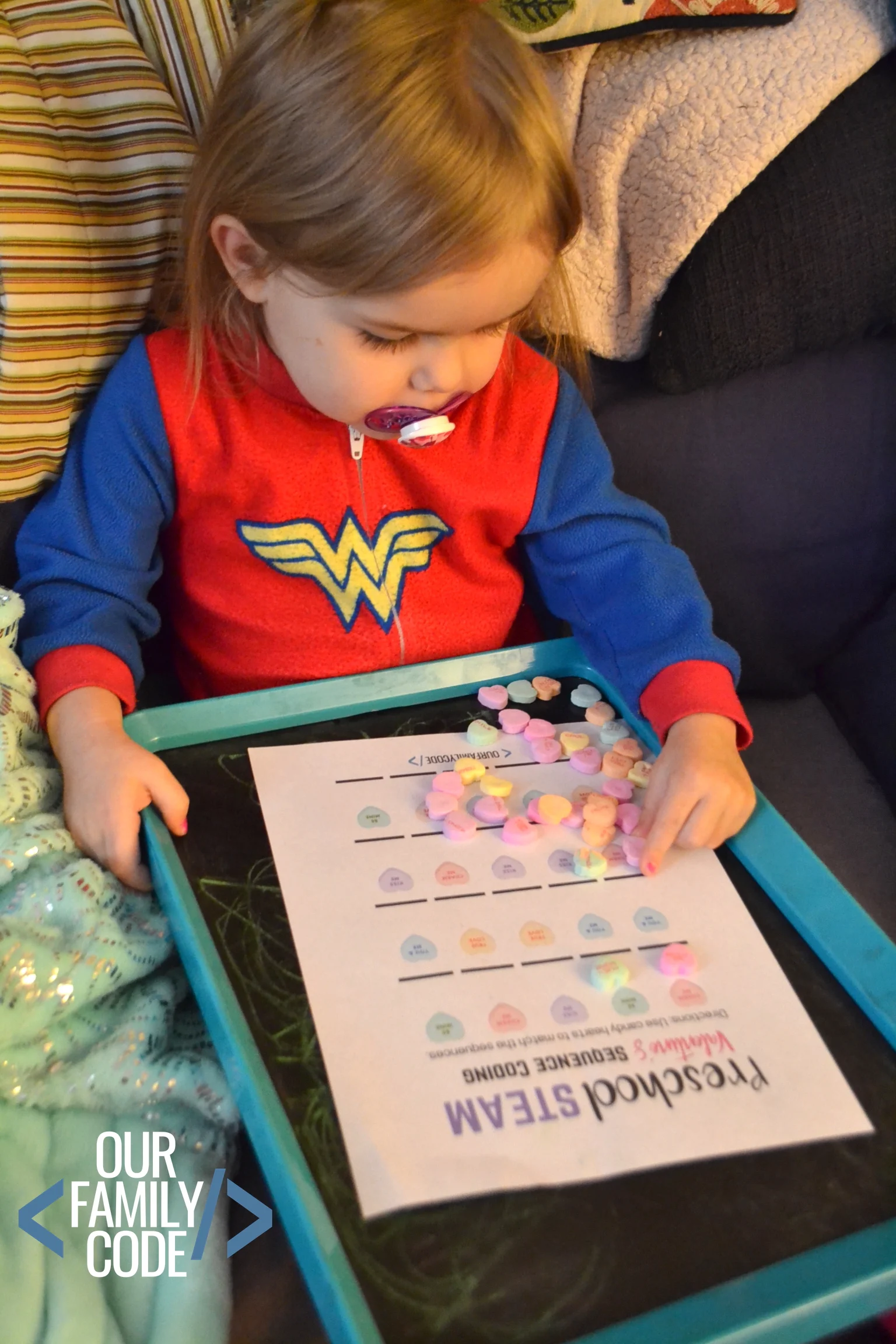A picture of a preschooler writing sequences with candy hearts for Valentine's Day coding activity.