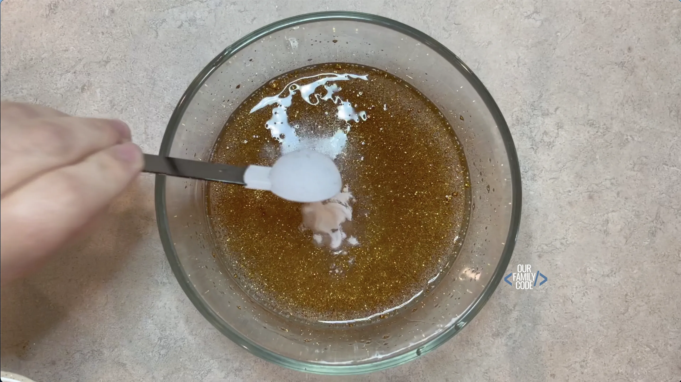 A picture of baking soda being added to saline solution slime recipe.