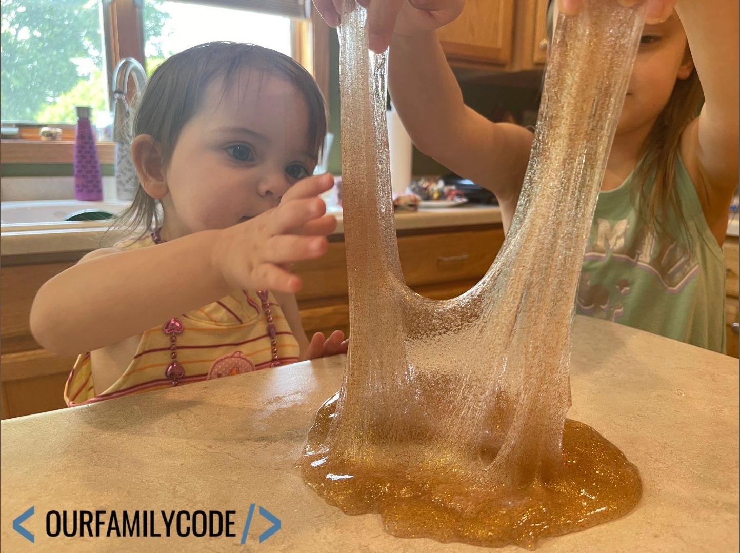 A picture of a toddler playing with gold glitter slime.