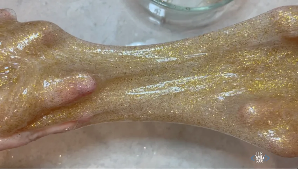 A picture of hands kneading saline solution slime recipe glitter slime.